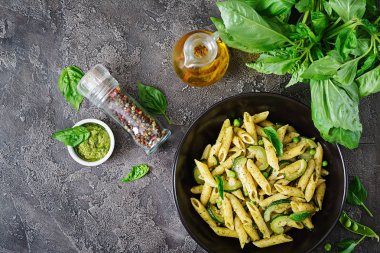Pesto sos, kabak, yeşil bezelye ve fesleğen ile penne makarna. İtalyan yemeği. Üstten görünüm. Düz kopya alanı ile yatıyordu