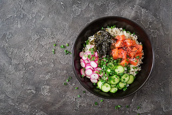 Hawaiian salmon fish poke bowl with rice, radish,cucumber, tomato, sesame seeds and seaweeds. Buddha bowl. Diet food. Top view. Flat lay