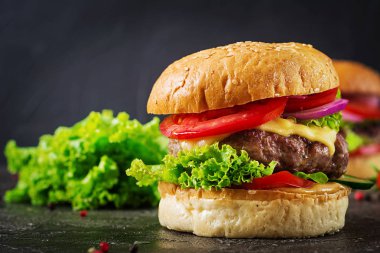 Koyu arka plan üzerinde taze sebze ve sığır eti burger hamburger. Lezzetli yemekler.