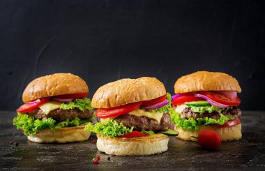 Sığır eti ve taze sebze kopya alanı ile koyu arka plan üzerinde üç hamburger