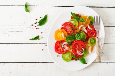 Renkli domates salatası soğan ve fesleğen pesto ile. Vegan gıda. Üstten görünüm. Düz yatıyordu