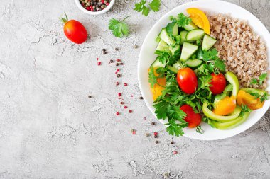 Diyet menüsü. Sağlıklı vejetaryen salata taze sebze - domates, salatalık, tatlı biber ve kupa yulaf lapası. Vegan gıda. Düz yatıyordu. Üstten görünüm