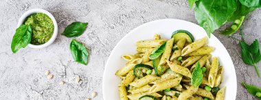 Pesto sos, kabak, yeşil bezelye ve fesleğen ile penne makarna. İtalyan yemeği. Üstten görünüm. Düz yatıyordu. Afiş