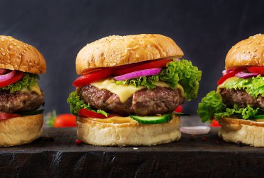 Koyu arka plan üzerinde taze sebze ve sığır eti burger hamburger. Lezzetli yemekler.