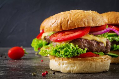 Koyu arka plan üzerinde taze sebze ve sığır eti burger hamburger. Lezzetli yemekler.