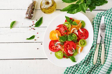 Beyaz ahşap arka plan yeşil peçete ile kopya alanı ile üstten görünüm soğan ve fesleğen pesto ile domates salatası