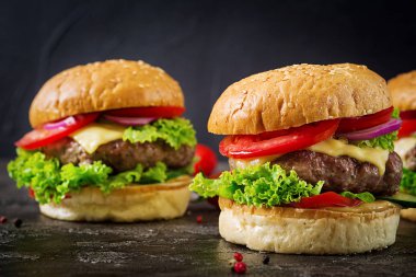 Koyu arka plan üzerinde taze sebze ve sığır eti burger hamburger. Lezzetli yemekler.