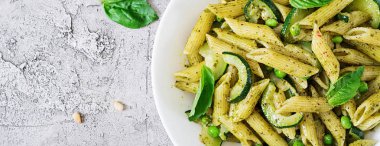 Pesto sos, kabak, yeşil bezelye ve fesleğen ile penne makarna. İtalyan yemeği. Üstten görünüm. Düz yatıyordu. Afiş