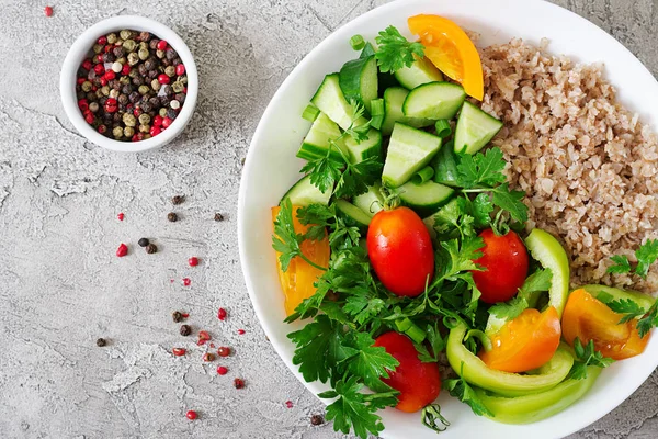 Diet menu. Healthy vegetarian salad of fresh vegetables - tomatoes, cucumber, sweet peppers and porridge on bowl. Vegan food. Flat lay. Top view