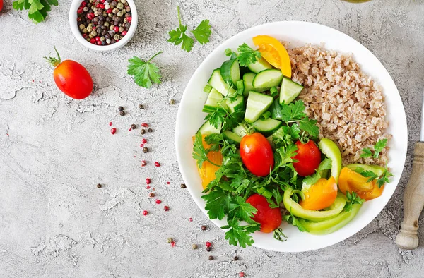 Diet menu. Healthy vegetarian salad of fresh vegetables - tomatoes, cucumber, sweet peppers and porridge on bowl. Vegan food. Flat lay. Top view