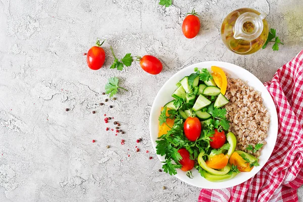 Diet menu. Healthy vegetarian salad of fresh vegetables - tomatoes, cucumber, sweet peppers and porridge on bowl. Vegan food. Flat lay. Top view