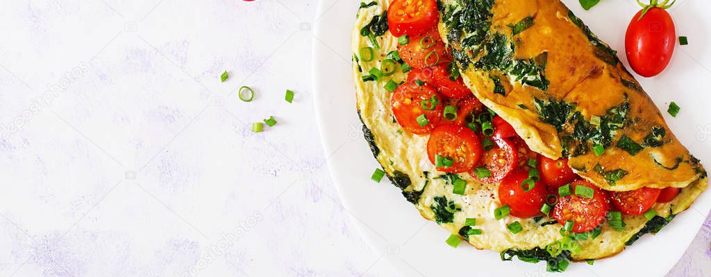 Omelette with tomatoes, spinach and green onion on white plate