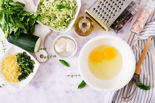 Ingredients for cooking frittata with zucchini, cheese and basil. Useful breakfast. Italian omelette. Top view. Flat lay.