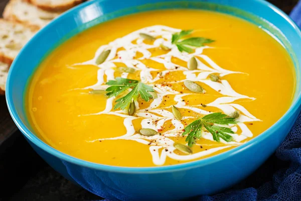 Pumpkin soup in bowl served with parsley and pumpkin seeds. Vegan soup. Thanksgiving day food. Halloween meal.
