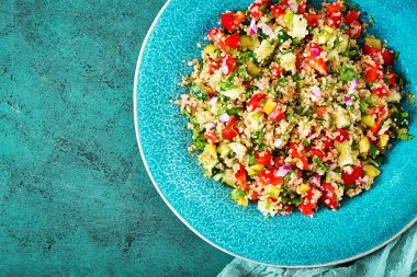Salata quinoa, roka, tatlı biber, domates ve salatalık kase karanlık bir arka plan üzerinde. Sağlıklı gıda, diyet, detoks ve vejetaryen kavramı. Tabbouleh salata. Üstten görünüm. Düz yatıyordu