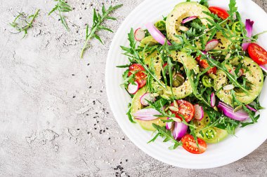 Diyet menüsü. Sağlıklı salata taze sebze - domates, avokado, roka, turp ve tohumlar üzerinde bir kase. Vegan gıda. Düz yatıyordu. Üstten görünüm