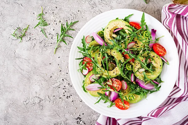 Diet menu. Healthy salad of fresh vegetables - tomatoes, avocado, arugula, radish and seeds on a bowl. Vegan food. Flat lay. Top view