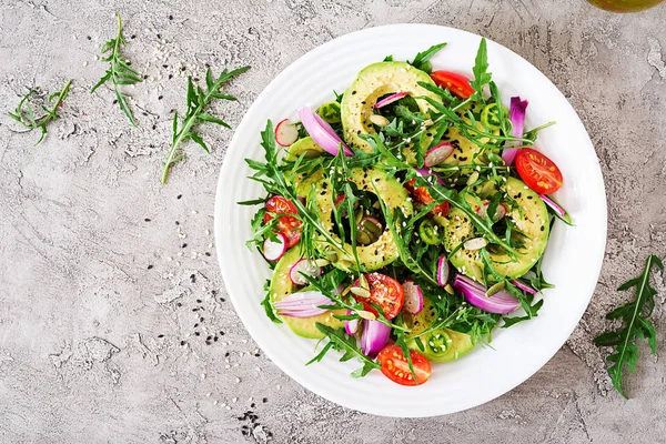 Diet menu. Healthy salad of fresh vegetables - tomatoes, avocado, arugula, radish and seeds on a bowl. Vegan food. Flat lay. Top view