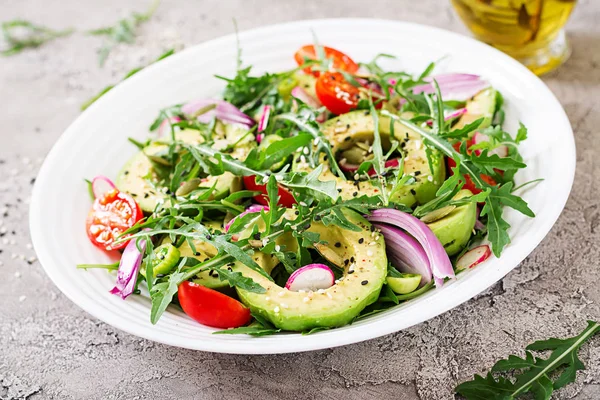 Diet menu. Healthy salad of fresh vegetables - tomatoes, avocado, arugula, radish and seeds on a bowl. Vegan food.