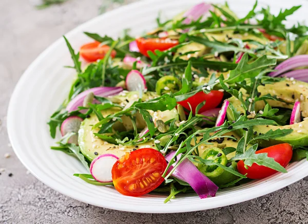 Diet menu. Healthy salad of fresh vegetables - tomatoes, avocado, arugula, radish and seeds on a bowl. Vegan food.