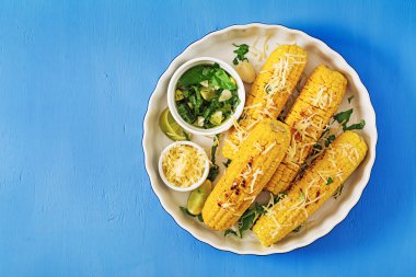 Fesleğen-sarımsak sosu ve kireç ile lezzetli ızgara Mısır. Lezzetli yemekler. Üstten görünüm. Düz yatıyordu