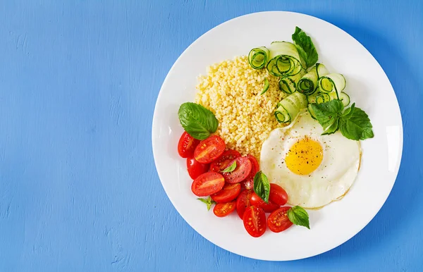 Healthy breakfast. Dietary menu. Millet porridge and tomato, cucumber salad and fried eggs. Top view. Flat lay