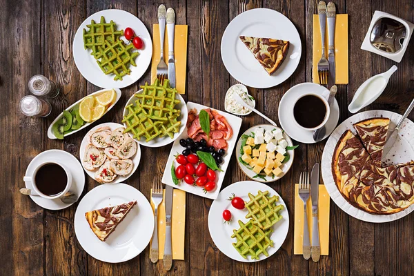 朝食用食品のテーブル お祝いブランチ セットは ほうれん草のワッフル サーモン チーズ オリーブ 鶏ロール チーズケーキと食事の様々 平面図です — ストック写真