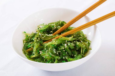 Wakame Chuka veya yosun salatası susam kase beyaz arka plan üzerinde. Geleneksel Japon yemekleri.