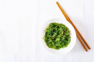 Wakame Chuka veya yosun salatası susam kase beyaz arka plan üzerinde. Geleneksel Japon yemekleri. Üstten görünüm. Düz yatıyordu