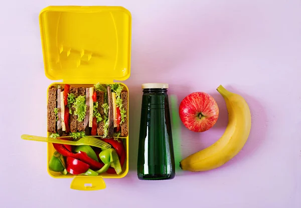 健康学校午餐盒与牛肉三明治和新鲜蔬菜 瓶水和水果在粉红色的背景 顶部视图 — 图库照片