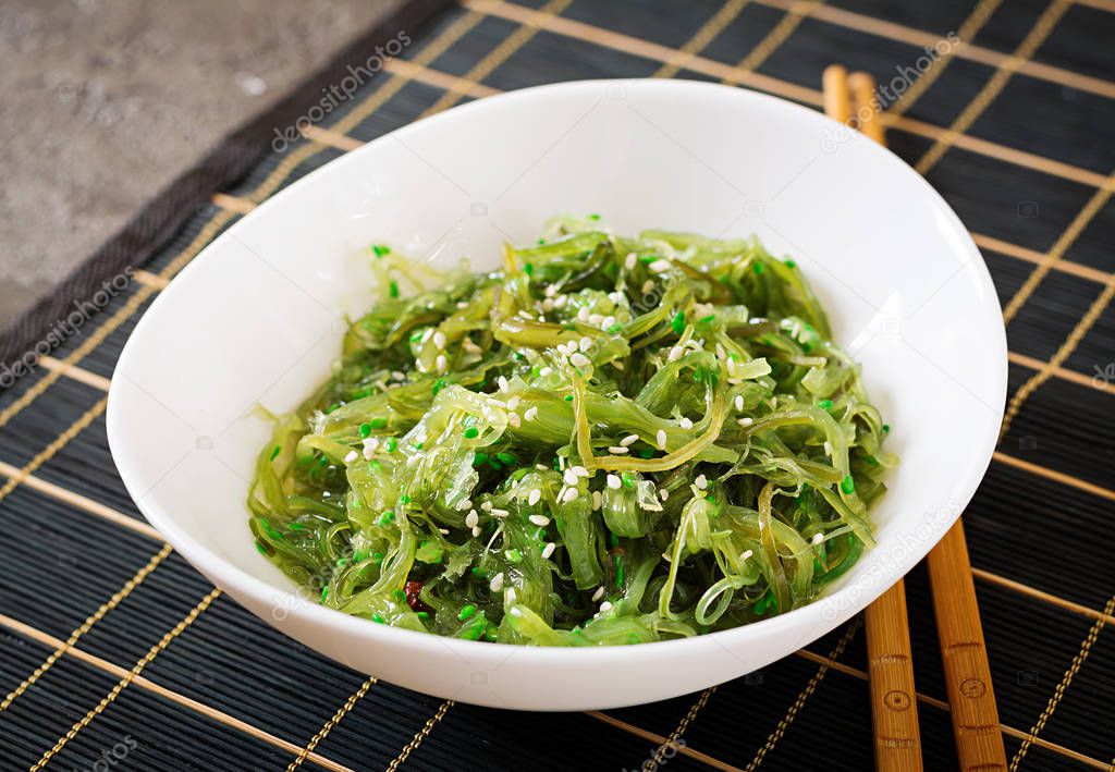 Wakame Chuka or seaweed salad  with sesame seeds in bowl on black background. Traditional Japanese food.