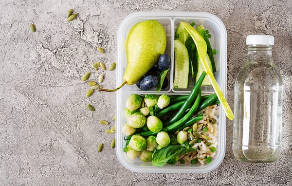 Vegan green meal prep container with  rice, green beans,  brussel sprouts, cucumber and fruits. Dinner in lunch box. Banner. Top view. Flat lay