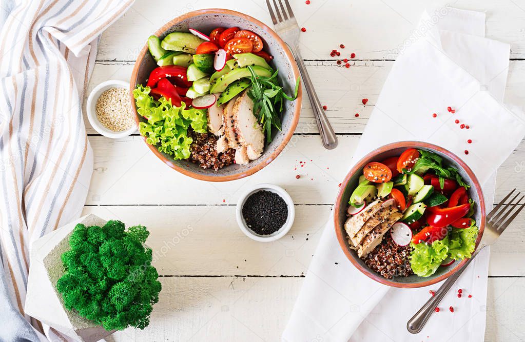 Buddha bowls with chicken fillet, quinoa, avocado, sweet pepper and various vegetables on white table
