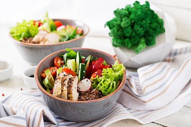 Buddha bowls with chicken fillet, quinoa, avocado, sweet pepper and various vegetables on white table clipart