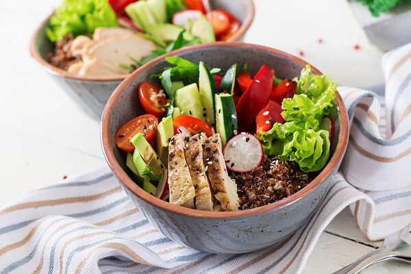 Buddha bowls with chicken fillet, quinoa, avocado, sweet pepper and various vegetables on white table