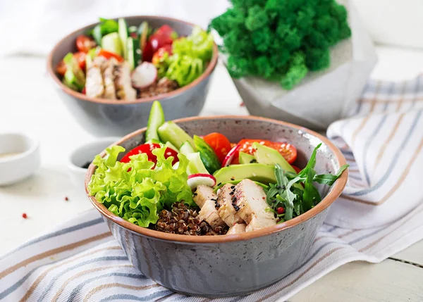 Buddha bowls with chicken fillet, quinoa, avocado, sweet pepper and various vegetables on white table