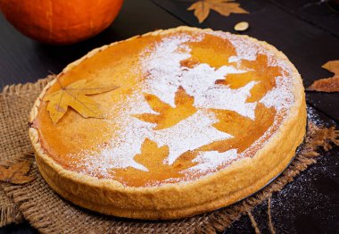 Tarçın, Hindistan cevizi, kabak çekirdeği ve ahşap masa üzerinde sonbahar yaprakları ile Amerikan ev yapımı kabak pasta. Şükran günü yemeği.