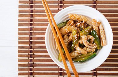 Tatlı Tay baharatlı salatası kalamar ve salatalık kopya alanı peçeteyle hasır üzerinde beyaz tabakta tatlı ve ekşi sos ile. Asya gıda.