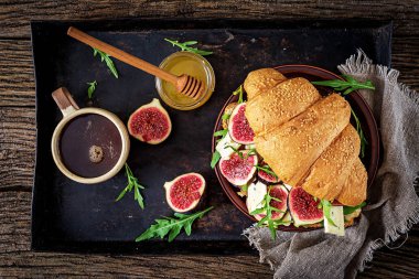 Brie peyniri roka ve incir ile taze kruvasan sandviç. Lezzetli kahvaltı. Lezzetli yemekler. Düz yatıyordu. Üstten görünüm