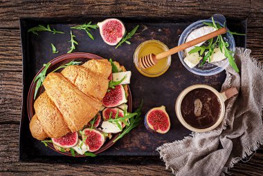 Brie peyniri roka ve incir ile taze kruvasan sandviç. Lezzetli kahvaltı. Lezzetli yemekler. Düz yatıyordu. Üstten görünüm