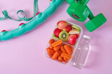 Fitness Ekipmanları. Sağlıklı gıda. Kavram sağlıklı yiyecek ve spor yaşam tarzı. Vejetaryen yemek. Halter, su, meyve pembe bir arka plan üzerinde. Üstten görünüm. Düz yatıyordu