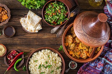 Geleneksel tajine yemekler, kuskus ve rustik ahşap masa üzerinde taze salata. Tagine kuzu eti ve kabak
