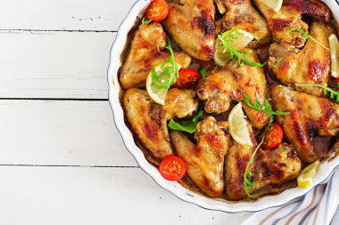 Ahşap masa tabakta tavuk kanatları pişmiş. Üstten görünüm.