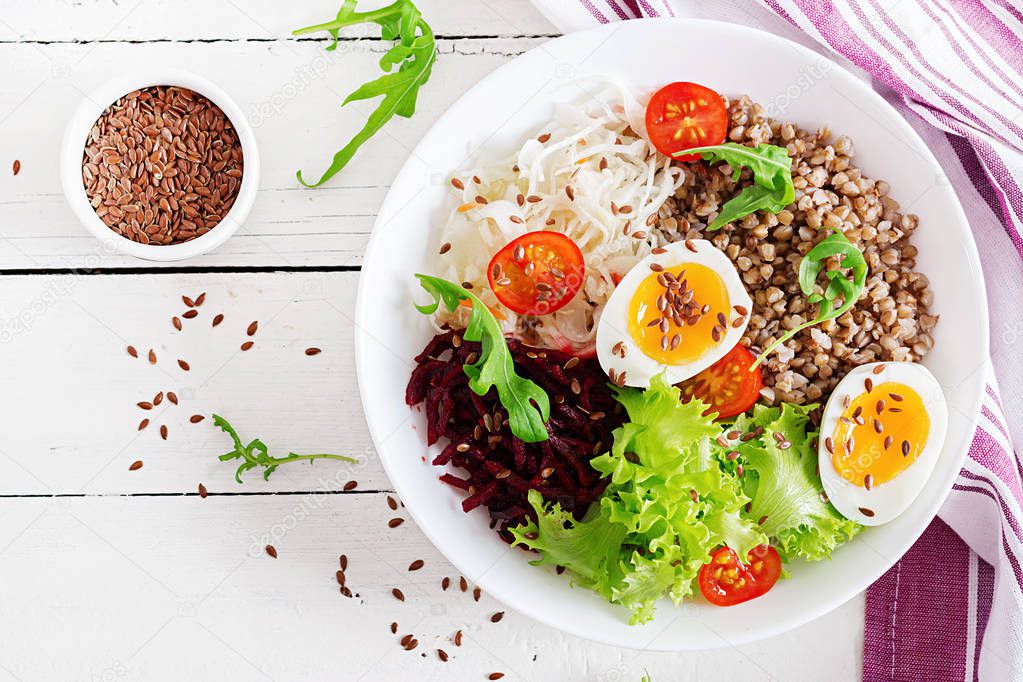 Buckwheat porridge buddha bowls with beetroot, cabbage, boiled eggs and  fresh tomato on white table. Healthy breakfast. Top view