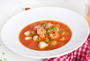 Brezilya gıda: balık ve biber baharatlı Hindistan cevizi soslu Beyaz ahşap bir masa üzerinde bir tabak içinde Moqueca capixaba. Brezilyalı balık güveç.