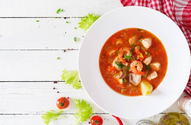 Brazilian food: Moqueca capixaba of fish and bell peppers in spicy coconut sauce  in a plate on a white wooden table. Brazilian fish stew. Top view clipart