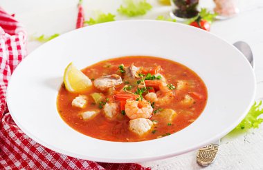 Brazilian food: Moqueca capixaba of fish and bell peppers in spicy coconut sauce  in a plate on a white wooden table. Brazilian fish stew. clipart