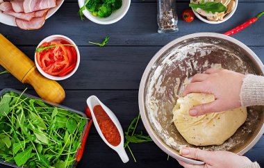 İtalyan pizza. Hamur Hazırlık pizza ve pasta malzemeler üzerinde masasına ile çalışan eller. Hamur, peynir, domates, brokoli, mantar, salam, jambon, tavuk fileto veya pişirme. Üstten görünüm