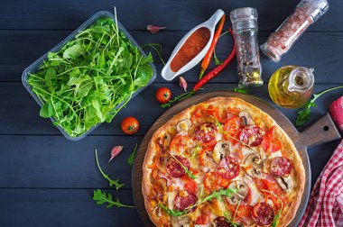 Tavuk fileto, mantar, jambon, salam, domates, peynir siyah bir zemin üzerine taze İtalyan pizza. İtalyan yemeği. Üstten görünüm