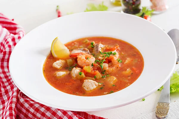 Brazilian food: Moqueca capixaba of fish and bell peppers in spicy coconut sauce  in a plate on a white wooden table. Brazilian fish stew.